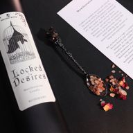 Primer plano de la etiqueta de la vela Locked Desires con un murciélago dentro de una jaula